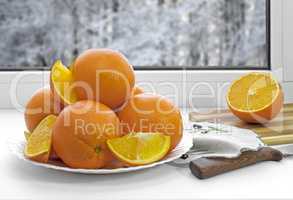Oranges on a plate on the sill of the window.