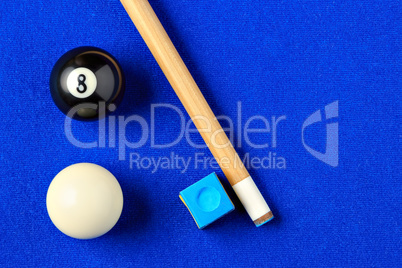 Billiard balls, cue and chalk in a blue pool table.