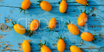 Yellow small tomatoes on blue wooden surface. Flat lay,top view.