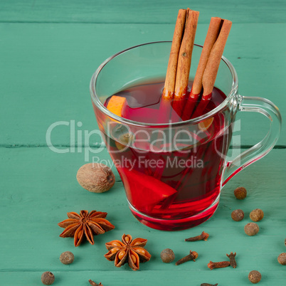 Hot red mulled wine on wooden background with spices.