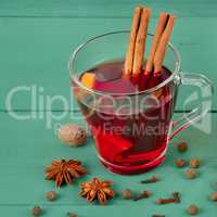 Hot red mulled wine on wooden background with spices.