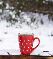 red ceramic mug in a white polka dots with coffee