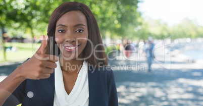 woman in park smiling with thumbs up