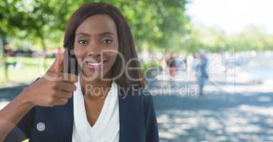 woman in park smiling with thumbs up