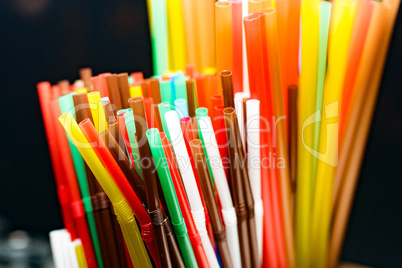 colored plastic cocktail tubes standing in a glass top view, Drinking straws
