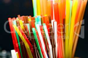 colored plastic cocktail tubes standing in a glass top view, Drinking straws