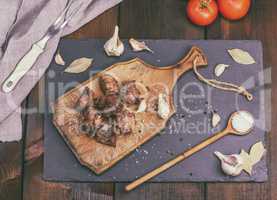 pieces of fried pork on a brown wooden board with spices