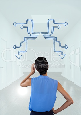 Thinking or confused woman from the back looking at arrows in a corridor