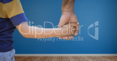 Child holding adults hand with blue wall in room