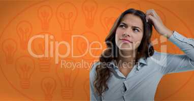 Confused woman scratching her head looking up in front of a orange background with bulbs