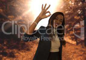 woman in forest smiling with ok sign