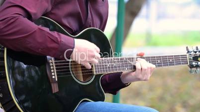 Young man playing acoustic guitar outdoors