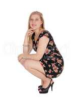 Beautiful young woman in a dress crouching