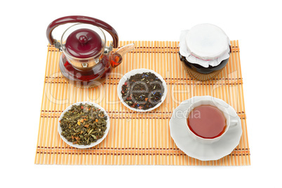 Teapot, cup of tea, jam jar and tea leaves isolated on white bac