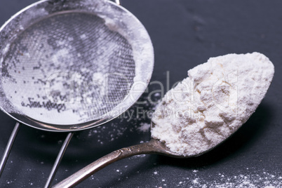 white wheat flour in an iron spoon