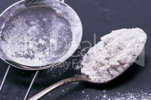 white wheat flour in an iron spoon