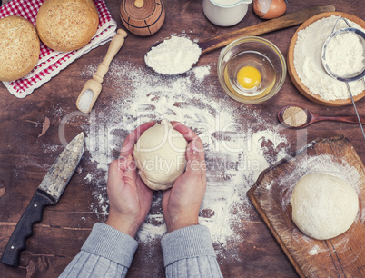 women's hands hold a ball of yeast dough