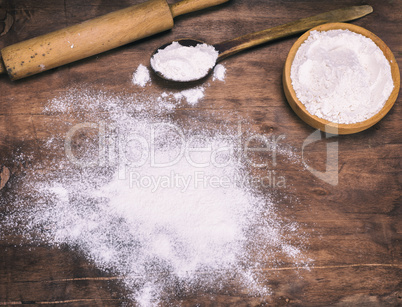 scattered white wheat flour on a brown wooden background