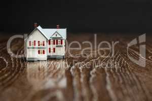 Model Home on Reflective Wooden Surface.