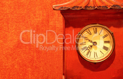 Antique red clock timepiece on a red wallpaper