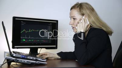 female trader talking on the phone and watching currency exchange chart at the computer monitor. Work on a crypto stock exchange