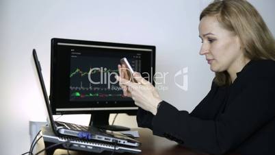 Business lady advises client on a phone and watching currency exchange chart at the computer monitor. Work on a crypto stock exchange