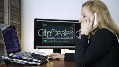 Business lady advises client on a phone and watching currency exchange chart at the computer monitor. Work on a crypto stock exchange