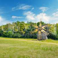 Old wooden windmill in a field and sky.