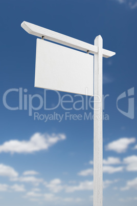 Blank Real Estate Sign Over A Blue Sky with Clouds.