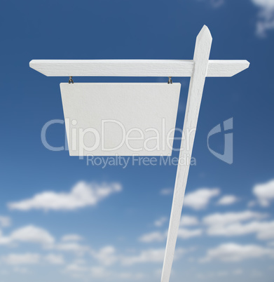 Blank Real Estate Sign Over A Blue Sky with Clouds.