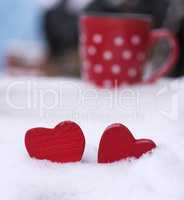 two wooden red hearts on the snow