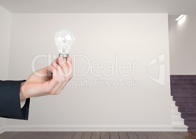 Hand holding light bulb in room