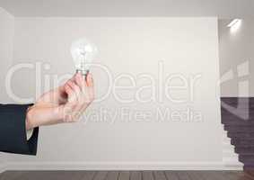 Hand holding light bulb in room