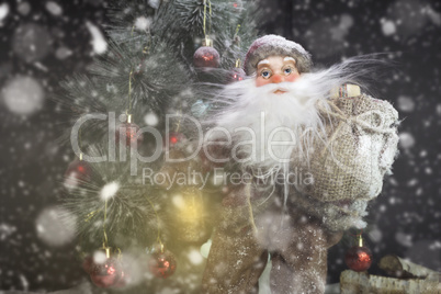 Santa Claus Outdoors Beside Christmas Tree in Snowfall Carrying