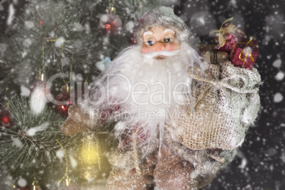 Santa Claus Outdoors Beside Christmas Tree in Snowfall Carrying