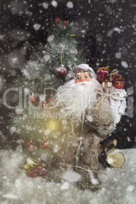 Santa Claus Outdoors Beside Christmas Tree in Snowfall Carrying