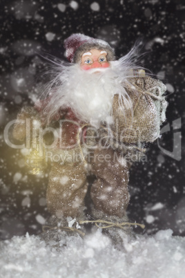 Santa Claus Outdoors Beside Christmas Tree in Snowfall Carrying