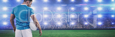 Composite image of rugby player standing with ball