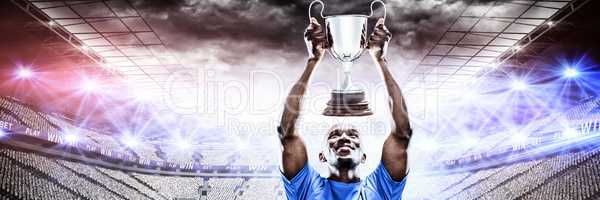 Composite image of happy sportsman looking up while holding trophy