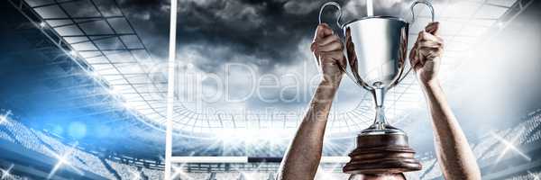 Composite image of successful rugby player holding trophy