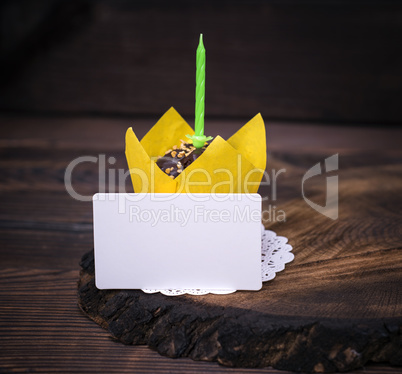 paper business card and chocolate cupcake with a green candle