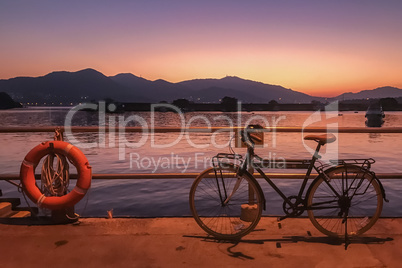 Silhouette of bicycle, fence and sea at sunset