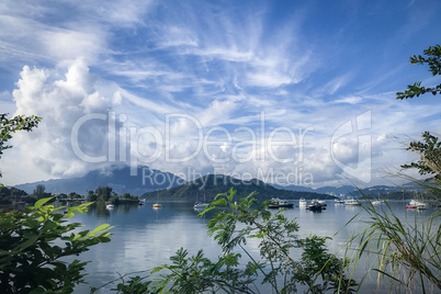 Green plants, mountain, blue sky, boats, yacht and sailboats on