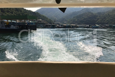 Back view of the white motor yacht leaving from pier