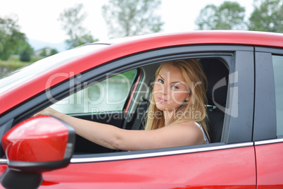 Frowning young blonde girl  in red car