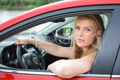 Young blue-eyed blonde looks through the car window