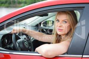 Young blue-eyed blonde looks through the car window