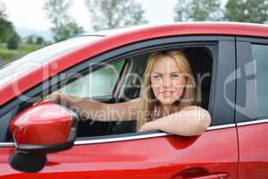 Young smiling and satisfied blonde girl  in red car