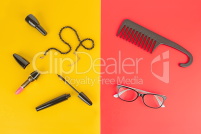 Glasses, cosmetics, jewelry and comb on a yellow and red backgro