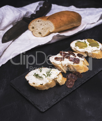 sandwiches with creamy white cheese, sausage, olives and dill